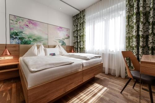 a bedroom with a bed and a desk and a window at Hotel Süd Graz in Graz