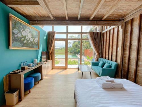 a bedroom with blue walls and a bed and a couch at Nglaras Resort Yogyakarta in Ngaglik