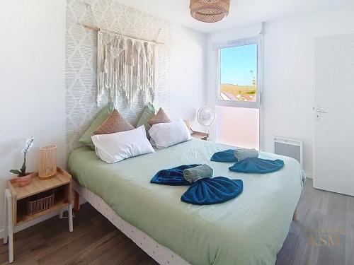 a bedroom with a bed with blue sheets and a window at L'Échappée Verte - T2 avec balcon in Saulx-les-Chartreux