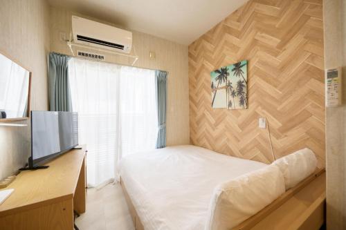 a small bedroom with a bed and a television at New Normal Condo in KENCHOMINAMIGUCHI ニューノーマルコンドイン県庁南口 in Naha