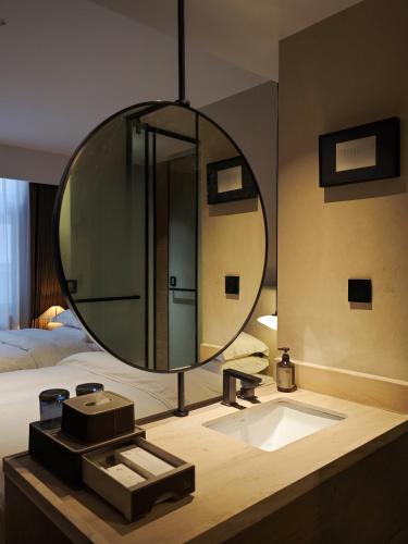 a bathroom with a sink and a large mirror at Wuye WOO YEAH Tangchi Hotel in Emeishan City