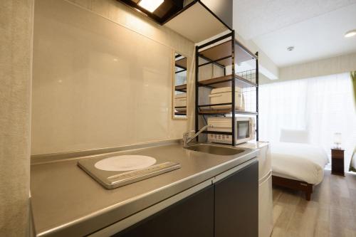 a bathroom with a sink and a bed in a room at New Normal Condo in KENCHOMINAMIGUCHI ニューノーマルコンドイン県庁南口 in Naha