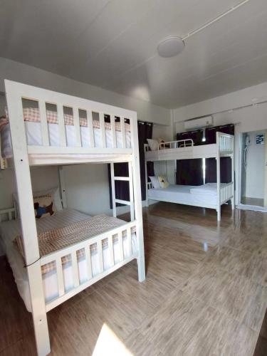 two white bunk beds in a room with wooden floors at Comfy Hotels Self Check in คอมฟี่โฮเทล เช็คอินด้วยตัวเอง in Samut Prakan