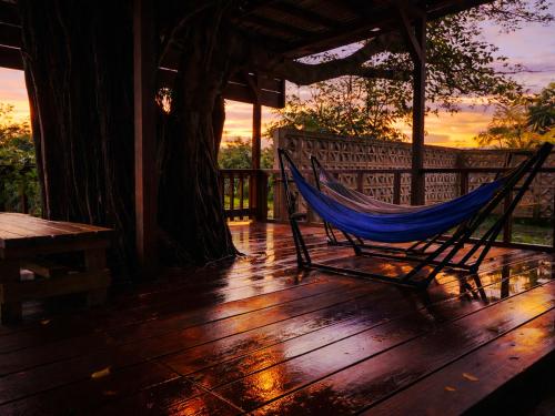 a hammock sitting on a deck with a tree at House&Cafe GreenTerrace in Ishigaki Island