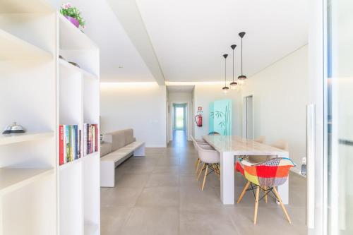 a dining room and living room with white walls and a table and chairs at Vila Praia Grande in Sines