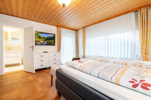 a bedroom with a large bed and a television at Alpen Lodge Chiemgau in Schleching