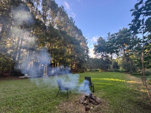 a fire in a yard with a chair in the grass at The Secret Place by Tiny Away in Palmvale