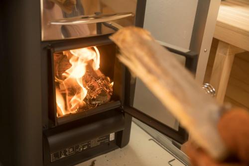 a person is putting food into an oven at Gracieux Villa Lusso in Miyakojima