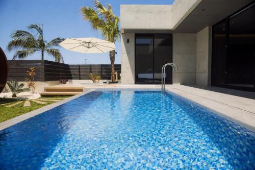 a swimming pool in front of a house at Gracieux Villa Lusso in Miyakojima