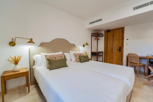 a bedroom with a large white bed and a table at Hotel Boutique Petit París in Port de Pollensa