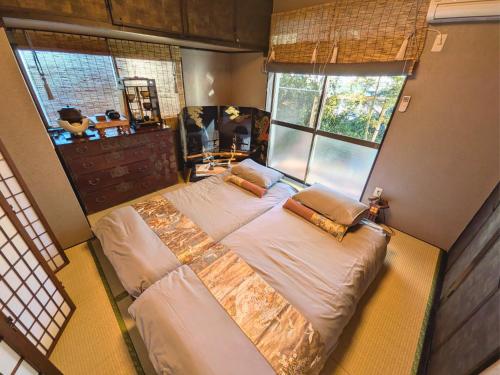 a large bed in a bedroom with two windows at 忍 Shinobi House in Yokohama