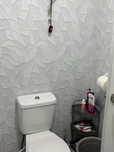 a bathroom with a white toilet and a wall at Private Villa in Masbate