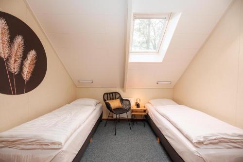 two beds in a room with a chair and a window at De Vuursteen | 10 - 40 pers. in Losser
