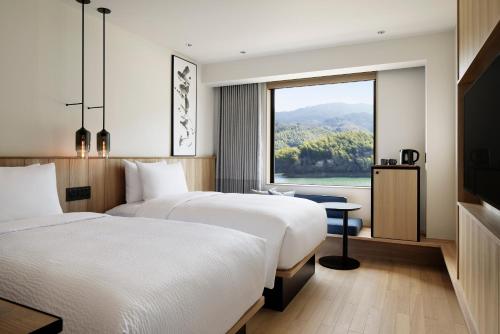 two beds in a hotel room with a window at Fairfield by Marriott Nara Tenri Yamanobenomichi in Tenri