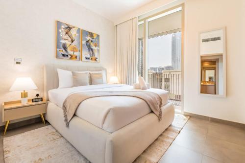 a white bedroom with a large bed and a window at Luxury 2 Bedroom Poolside Haven in Dubai Creek Harbour in Dubai