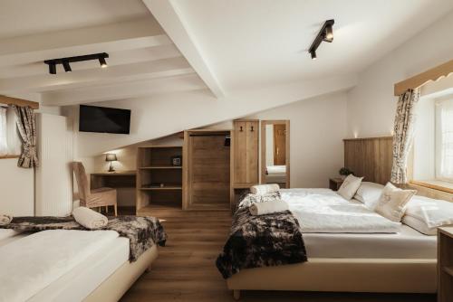 a bedroom with two beds and a tv at Hotel Monte Cherz in Arabba