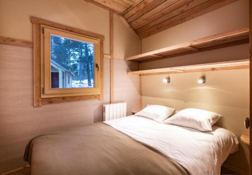 a bedroom with a bed and a window at Huttopia Bozel en Vanoise in Bozel