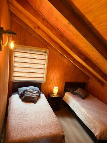 two beds in a room with wooden walls at Cabaña Amancay Fuy in Puerto Fuy