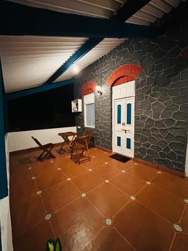 a room with a stone wall and a door and chairs at The Coastal Nest in Daman