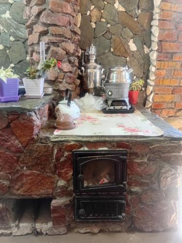 a stone kitchen with a stove with pots and pans at JAPAR guest house in Bokonbayevo