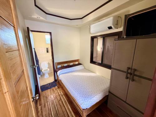 a small room with a bed and a toilet at Pads Guesthouse in San Vicente