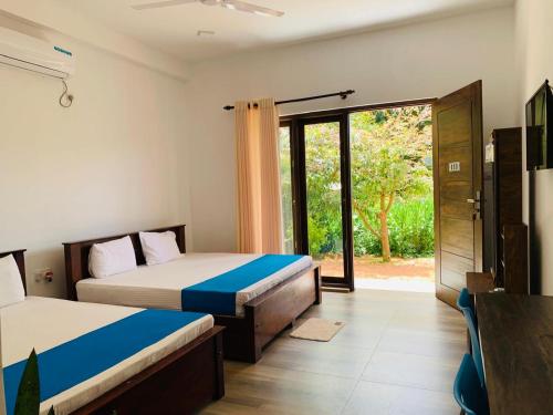 a bedroom with two beds and a sliding glass door at Grandmila Resort in Anuradhapura