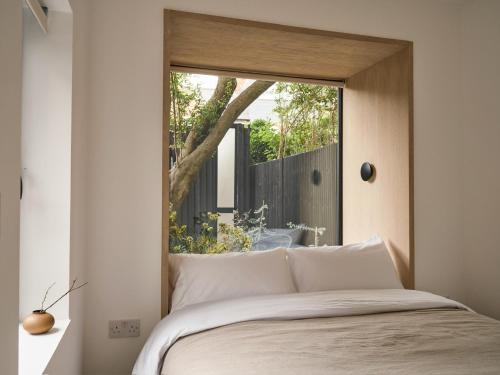 a bedroom with a large window above a bed at Elegant 3BR Garden Flat - Steps from Central Oxford in Oxford