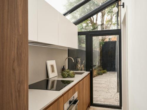 a kitchen with white cabinets and a large window at Elegant 3BR Garden Flat - Steps from Central Oxford in Oxford
