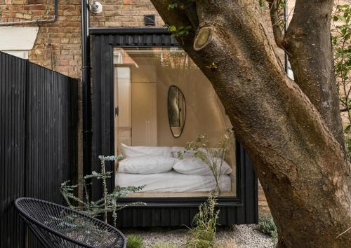 a bed in a window next to a tree at Elegant 3BR Garden Flat - Steps from Central Oxford in Oxford