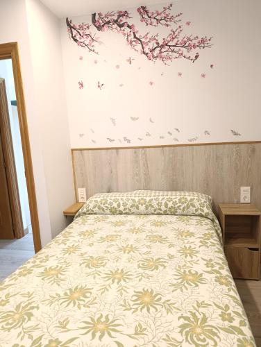 ein Schlafzimmer mit einem Bett mit einer geblümten Tagesdecke in der Unterkunft Trisquel 2 in Laroá