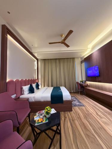 a hotel room with a bed and purple chairs at The Infinity Hotel in Kānpur