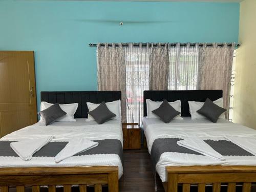two beds sitting next to each other in a bedroom at Raaha Residency in Mysore