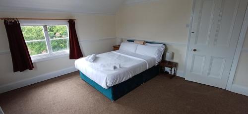 a bedroom with a bed with white sheets and a window at Brookside Lodge, central Dawlish in Dawlish