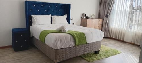 a bedroom with a large bed with a blue headboard at Ayjalon Guest Home in Ludeke