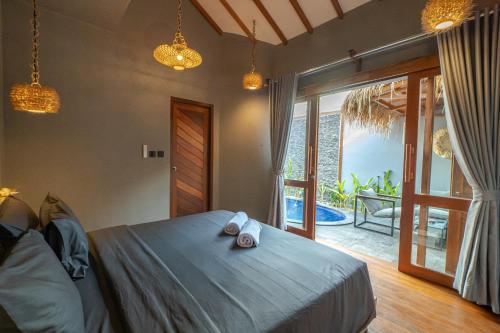 a bedroom with a bed and a sliding glass door at Gili Nomade Villas in Gili Trawangan