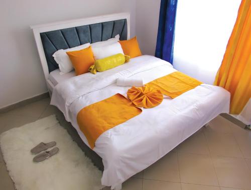 a bed with orange and yellow pillows andippers on it at Nolan's Comforts Kitengela in Kitengela 