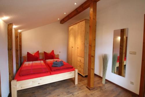 a bedroom with a red bed and a wooden door at Ferienwohnung an der südlichen Boddenküste in Bartelshagen