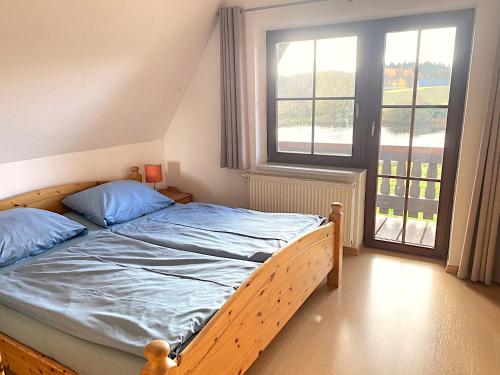 a bedroom with a bed with blue sheets and a window at Finnhaus Lisa in Marlow