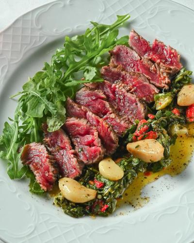 a plate of food with meat and greens on it at Carmella Spa & Boutique Hotel in Haifa