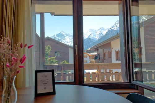 a room with a table with a view of mountains at La Collina Coliving and Coworking in Grächen