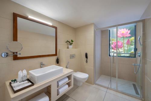 a bathroom with a sink and a toilet and a mirror at Olivia International in Alleppey