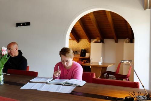 a woman sitting at a table reading books at La Collina Coliving and Coworking in Grächen