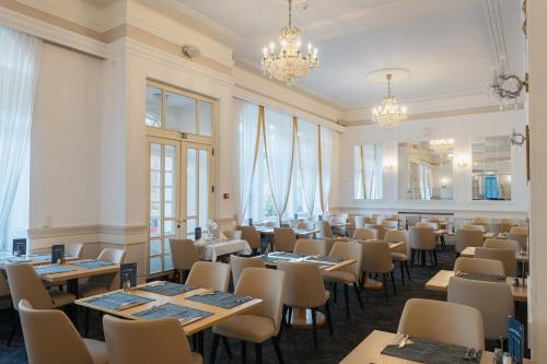 a dining room with tables and chairs and windows at OREA Spa Hotel Palace Zvon Mariánské Lázně in Mariánské Lázně