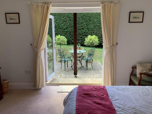 a bedroom with a bed and a patio with a table and chairs at Riverdown B&B in Exeter