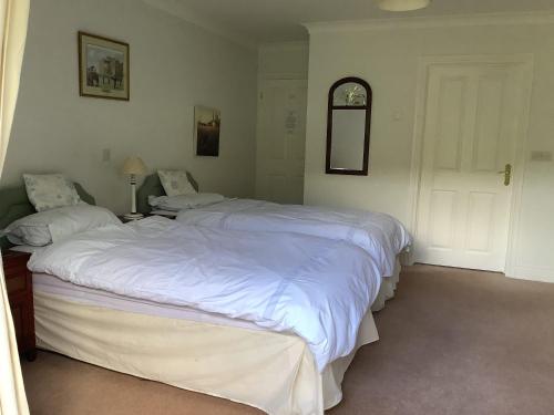 a bedroom with two beds with white sheets at Riverdown B&B in Exeter
