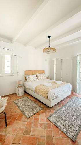 a white bedroom with a large bed and a chandelier at Casa do Sol - Casas do Levante in Olhão