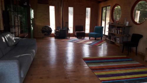 a living room with a couch and chairs on a wooden floor at Cabañas & SPA Carilafquen in Laguna Verde
