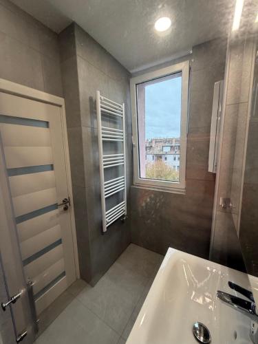 a bathroom with a tub and a window and a sink at K&T Apartman in Szentendre