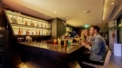 a man and a woman sitting at a bar at Hotel Aqua Citta Naha in Naha