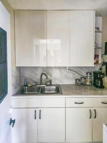 a kitchen with white cabinets and a sink at Studio Efficiency Apartment - a peaceful retreat in Port St Lucie in Port Saint Lucie